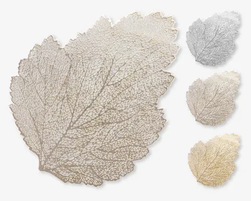 Dekorativ dækkeserviet formet som et blad, med detaljerede udskæringer, der efterligner bladets naturlige årestruktur. Dækkeservietten fås i tre farver: sølv, beige og guld, som vist på billedet. Designet er fint og elegant, velegnet til at give borddækningen et stilfuldt udtryk.