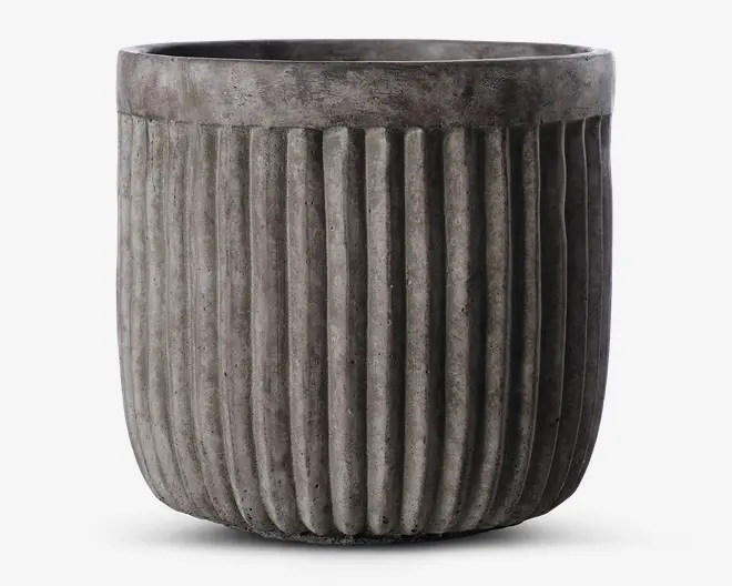 En rund, grå potte med lodret riflede sider. Overfladen har et betonlignende udseende, hvilket giver et moderne og industrielt præg. Den øverste kant er glat og en smule bredere end selve kroppen, hvilket skaber en diskret kant.