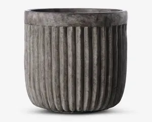 En rund, grå potte med lodret riflede sider. Overfladen har et betonlignende udseende, hvilket giver et moderne og industrielt præg. Den øverste kant er glat og en smule bredere end selve kroppen, hvilket skaber en diskret kant.