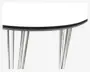 Nærbillede af et bord med en glat, rund hvid bordplade og sort kant. Bordet har fire skrå, krombelagte metalben, der giver et moderne og solidt udtryk.