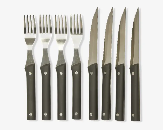Sæt med fire matchende gafler og fire matchende steakknive, alle med sorte håndtag og to synlige metalnitter. Håndtagene er lige og har en mat overflade, mens knivbladene er savtakkede til udskæring. Gaffel-tænderne er jævnt fordelt, og det samlede design er enkelt og moderne.