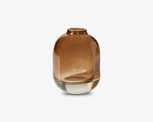 Rund, transparent glasvase med en varm ravfarvet tone. Vasens bund er tyk og klar, og den har en lille, smal åbning foroven. Den glatte overflade og de diskrete farvenuancer giver et moderne og elegant udtryk.