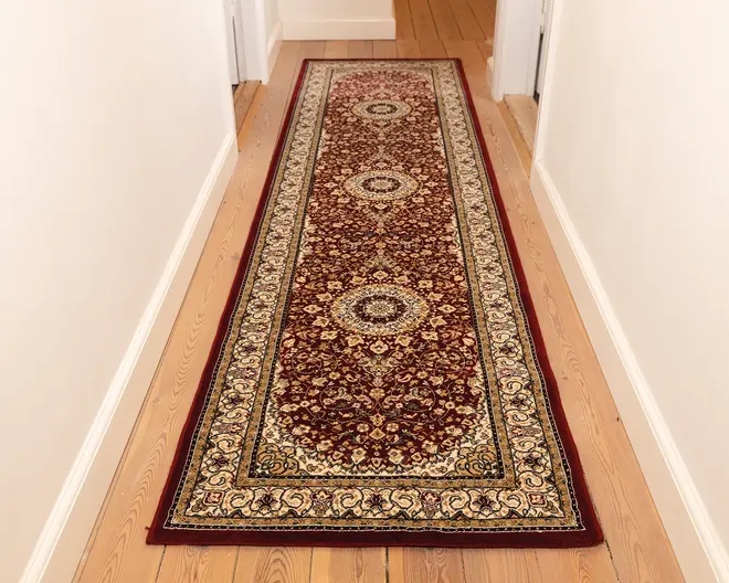 Lang, rektangulær løber med en dyb bordeaux baggrund og detaljerede blomstermønstre i creme, guld og marineblå. Har tre store medaljonmotiver jævnt fordelt langs midten. Kanten er dekoreret med udsmykkede snørklede og blomsterdesigns i creme og guld nuancer. Tæppet har lav luv og ser tæt vævet ud, hvilket gør det velegnet til områder med meget trafik som gange.