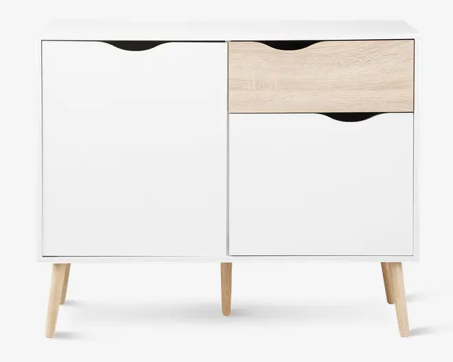 Et moderne skab med et minimalistisk design, hvid finish og detaljer i naturtræ. Skabet står på fire skrå træben, har to store hvide låger og en skuffe i lyst træ med buet udskæring som greb. Grebene er integreret i toppen af hver låge og skuffe for et stilrent, grebsfrit udtryk.