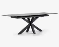 Rektangulært bord med mat sort finish, der har en glat, flad bordplade og et markant geometrisk stel bestående af flere skråtstillede ben, der mødes i midten for et moderne, skulpturelt udtryk. Bordet fremstår robust og rummeligt, velegnet til spise- eller arbejdsbrug.