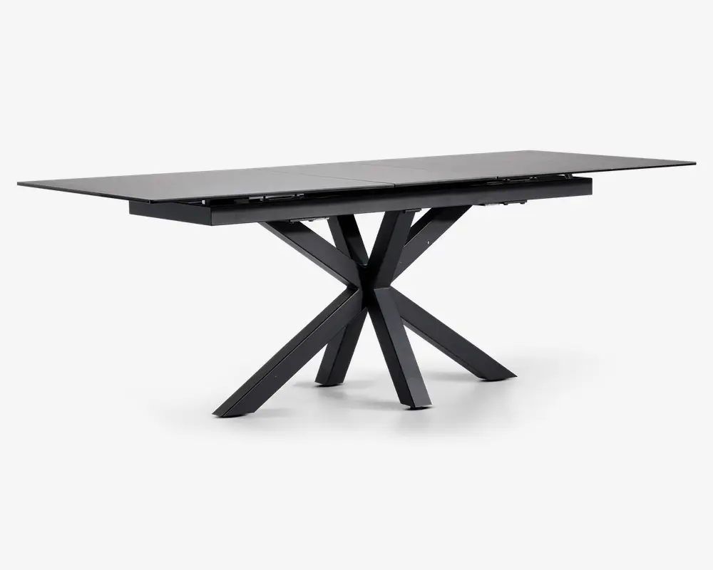 Rektangulært bord med mat sort finish, der har en glat, flad bordplade og et markant geometrisk stel bestående af flere skråtstillede ben, der mødes i midten for et moderne, skulpturelt udtryk. Bordet fremstår robust og rummeligt, velegnet til spise- eller arbejdsbrug.