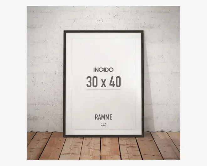 En rektangulær billedramme med en tynd, sort kant, der passer til kunstværker i størrelsen 30 x 40 cm. Rammen har et moderne, minimalistisk design og står oprejst mod en hvid, tekstureret væg på et trægulv. Fronten er klar glas eller akryl, og rammen har en glat, mat overflade.
