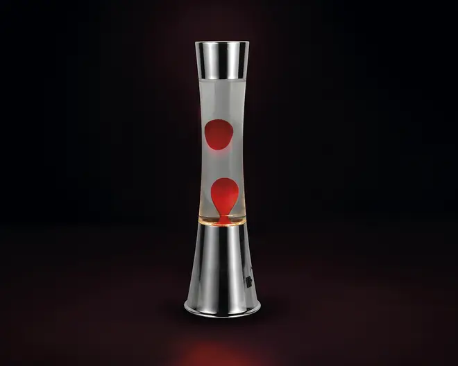 Høj, cylindrisk lampe med en elegant metalbase og top. Den gennemsigtige glasbeholder indeholder røde voksbobler, der er suspenderet i klar væske, hvilket skaber en dynamisk visuel effekt, når voksen bevæger sig og ændrer form ved opvarmning. Lampen har et moderne, poleret look og en tænd/sluk-knap på basen.