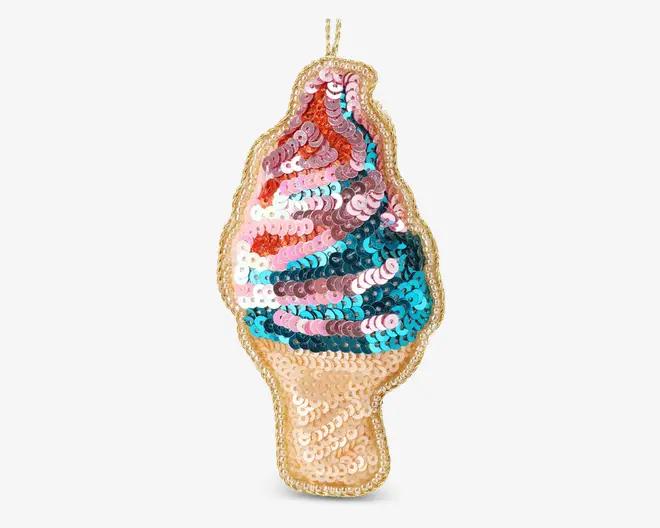 Patch formet som en softice-vaffel, dekoreret med skinnende pailletter i snoede mønstre af pink, blå, hvid og guld. Vaffeldelen er dækket af guldfarvede pailletter, og kanten er omkranset af en guldbort. Patchen har en løkke øverst til nem fastgørelse.