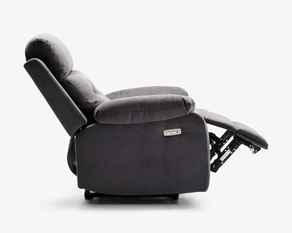 Sidebillede af en mørkegrå lænestol i fuldt tilbagelænet position. Stolen har bløde, polstrede armlæn og en polstret ryg for ekstra komfort. Fodstøtten er slået ud og understøttes af en synlig metalmekanisme. På siden er der et kontrolpanel med to knapper, hvilket indikerer elektrisk justering. Betrækket ser ud til at være af blødt stof.