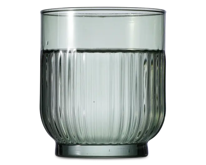 Kort drikkeglas med let afrundet bund og lodret rillet struktur på den nederste halvdel. Glasset er transparent med et diskret gråt skær, og kanten er glat og jævn. Designet giver et moderne og elegant udtryk, velegnet til servering af vand eller andre drikkevarer.