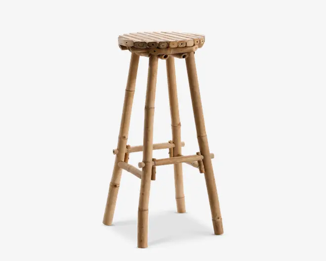 Høj taburet fremstillet af naturlig bambus med et rundt sæde bestående af tæt placerede bambussegmenter. Taburetten har fire solide, let skråtstillede ben, som er forstærket med både vandrette og diagonale bambusstøtter for ekstra stabilitet. Bambussen har sin naturlige farve og struktur, hvilket giver taburetten et rustikt og miljøvenligt udtryk.