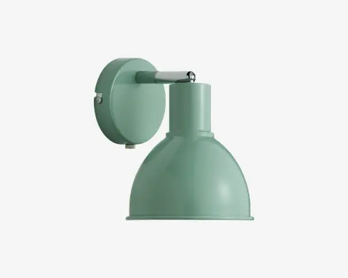 Væghængt lampe med mat, pastelgrøn overflade. Lampen har en rund vægplade og en kuppelformet skærm, der leder lyset nedad. Designet er minimalistisk og industrielt med synlige skruer på monteringspladen som en diskret dekoration.