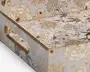 Rektangulær bakke med udskårne håndtag på siderne, dekoreret med et elegant, præget blomsterdesign i guld på en blank hvid baggrund. Blomster og blade er detaljeret udført, hvilket giver overfladen en tekstureret og luksuriøs fornemmelse. Kanterne er afsluttet med en guldfarvet kant, som understreger det sofistikerede udtryk.