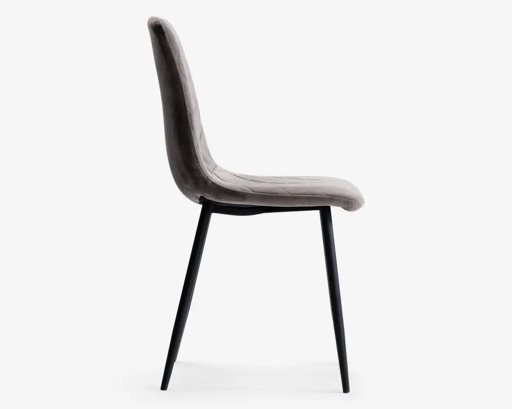 Sidebillede af en moderne stol med let buet, polstret ryg og sæde betrukket med blødt, lysegråt stof. Stolen har slanke, sorte metalben, der er let udadskrånende, hvilket giver et stilrent og minimalistisk udtryk. Sæde og ryg er sammenhængende og giver ergonomisk støtte.