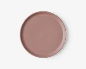 Rund tallerken med en glat, mat overflade i en afdæmpet rosa farve. Tallerkenen har en let forhøjet kant og et enkelt, minimalistisk design uden mønstre eller dekorationer.