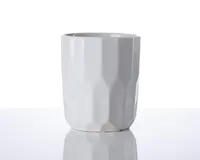En hvid keramikkop med et moderne, facetslebet design. Overfladen har geometriske, kantede mønstre, der giver koppen et tekstureret udseende. Koppen har en glat kant og en blank finish, hvilket giver et stilrent og moderne udtryk.