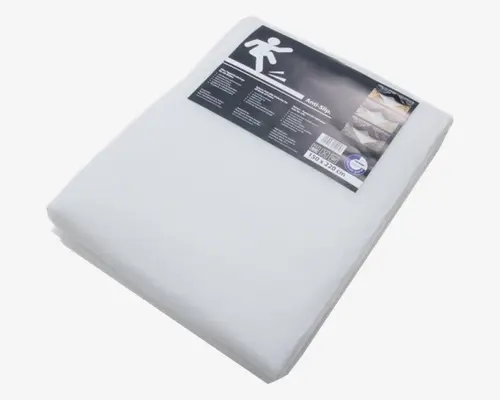 En sammenfoldet, hvid skridsikker underlag med glat overflade, pakket i klar plastik. Etiket på toppen viser produktinformation, herunder et grafisk ikon af en person der glider, og angiver størrelsen som 150 x 220 cm. Materialet virker let og er beregnet til at lægge under tæpper eller måtter for at forhindre, at de glider.