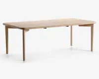 Rektangulært bord med en glat, lys træfinish. Bordpladen har blødt afrundede kanter og hjørner, og de fire ben er lige med en let tilspidsning, hvilket giver bordet et minimalistisk og moderne udtryk. Konstruktionen virker solid, og den naturlige træstruktur er synlig overalt.