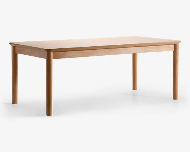 Rektangulært bord med en glat, lys træfinish. Bordet har afrundede hjørner og solide, cylindriske ben, der bliver en smule smallere mod bunden. Designet er minimalistisk og moderne med rene linjer og synlig træstruktur på overfladen.