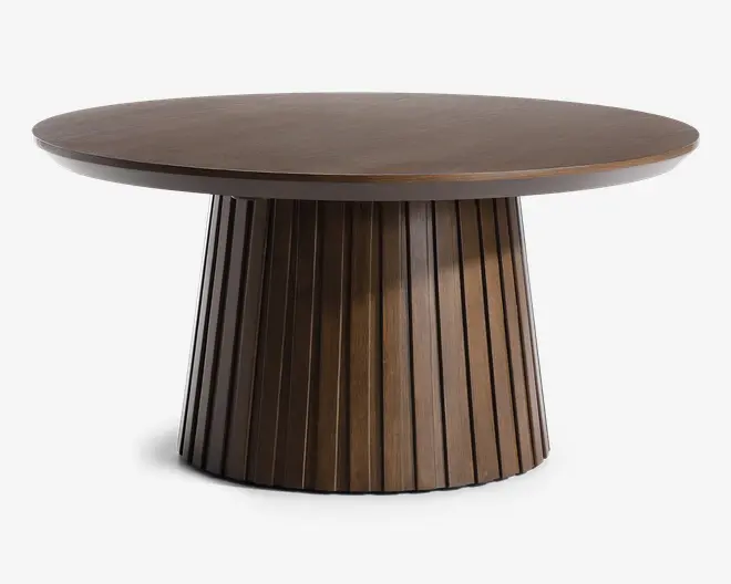 Rundt bord med en glat, flad træbordplade og en markant piedestalbase. Basen er cylindrisk og har lodrette lameller, hvilket giver et tekstureret og moderne udseende. Træet har en dyb, mørk finish, og det samlede design er moderne og elegant.