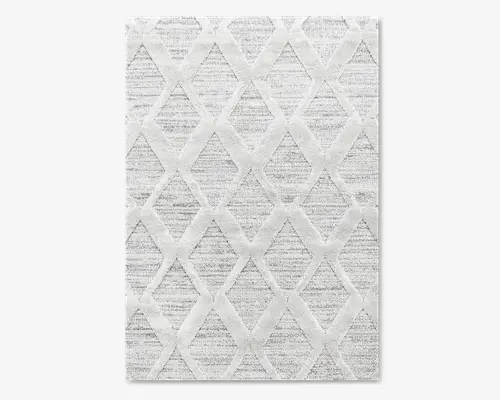 Rektangulært tæppe med en blød, lysegrå baggrund og et hævet geometrisk diamantmønster i en lidt lysere nuance. Teksturen virker blød og designet er moderne, hvilket giver et diskret, men interessant udtryk, mens farvepaletten holdes neutral. Kanterne er lige og rene, hvilket giver et moderne udtryk.