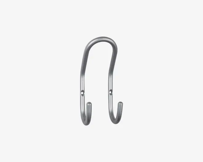 En metal dobbeltkrog med et glat, buet design og børstet finish. Krogen har to monteringshuller til sikker fastgørelse på væggen og to afrundede ender til ophængning af genstande. Det overordnede udseende er slankt og moderne, velegnet til både hjemmet og kontoret.