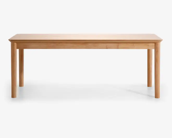 Rektangulært bord med en glat, lys træfinish. Bordet har rene, lige kanter på bordpladen og runde, solide ben. Designet er minimalistisk og moderne med synlig træstruktur, der giver et naturligt udtryk. Bordet virker rummeligt og egner sig til både spisning og arbejde.