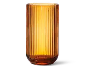 Høj, cylindrisk beholder lavet af ravfarvet glas med lodret rillet struktur. Glasset er gennemsigtigt, hvilket lader lyset skinne igennem og fremhæver den varme, gyldne farve. Kanten er glat, og bunden er en smule tykkere for ekstra stabilitet.
