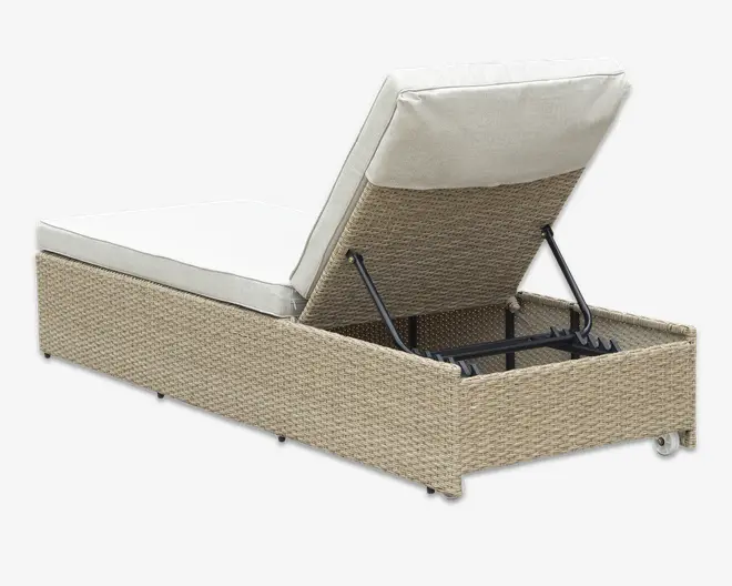 Beige loungestol i flettet rattan med en cremefarvet hynde, justerbar ryglæn understøttet af en sort metalramme. Basen har et opbevaringsrum under sædet, som kan tilgås ved at løfte ryglænet. Loungestolen er udstyret med små hjul for nem flytning.