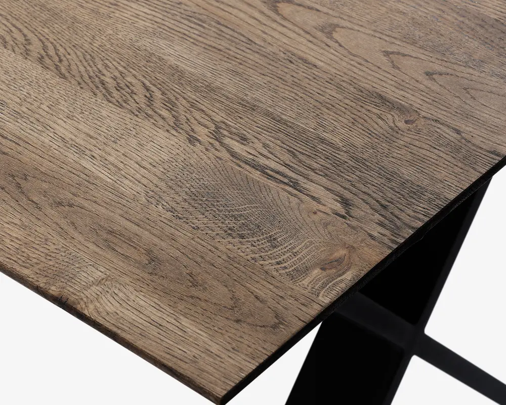 Nærbillede af en bordplade med naturlig træstruktur, der har en glat overflade og synlige knaster og årer. Kanten er lige og pæn, og bordet understøttes af en solid sort metalramme nedenunder.
