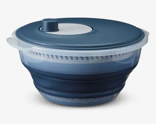 Sammenklappelig skål i blå og gennemsigtig plast med ventileret inderskål og matchende blåt låg med drejeknap i midten til nem spinning. Skålen er lavet af holdbar plast og silikone, så den kan foldes sammen for pladsbesparende opbevaring. Den klare yderskål gør det muligt at se indholdet, og den brede kant giver et sikkert greb.
