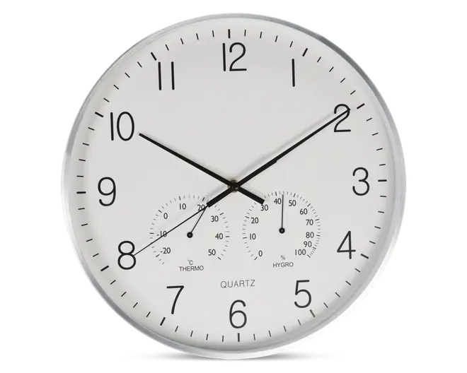 Rund vægur med hvid urskive og sorte tal, udstyret med tre sorte visere til timer, minutter og sekunder. Uret har også to små målere nederst: én til temperatur (termometer) og én til luftfugtighed (hygrometer), begge med tydelige markeringer og sorte visere. Rammen er sølvfarvet, og designet er minimalistisk og let at aflæse.
