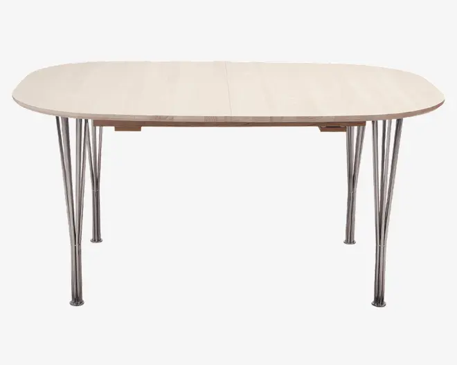 Ovalt bord med en lys træfinish og en glat, jævn overflade. Bordet har seks slanke, skråtstillede kromben, der giver et moderne udtryk og stabil støtte. Kanterne er blødt afrundede, og bordet har en synlig samling i midten, hvilket tyder på, at det muligvis kan udvides.