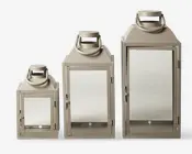 Sæt med tre lanterner i forskellige størrelser, hver med en rektangulær form, flad bund og glasfrontdør. Lanterne har en mat beige finish og et robust metalhåndtag øverst til nem transport eller ophængning. Dørene lukkes med en lås, og designet er enkelt og moderne, velegnet til både indendørs og udendørs brug.