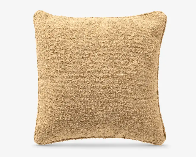 Firkantet beige pudebetræk med blødt, struktureret bouclé-lignende stof og let afrundede hjørner.