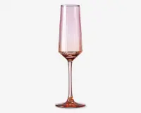 Høj, slank glas med fløjteformet skål og lang stilk, der har en diskret lyserød nuance over hele glasset. Skålen har lodrette riller, som giver struktur og et elegant udtryk, og foden er bred og stabil. Glasset har et moderne, stilfuldt design, der egner sig til servering af mousserende drikke.