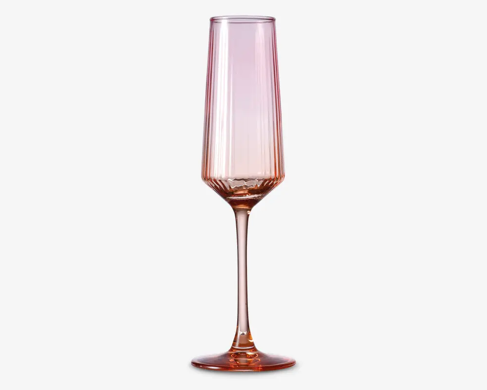 Høj, slank glas med fløjteformet skål og lang stilk, der har en diskret lyserød nuance over hele glasset. Skålen har lodrette riller, som giver struktur og et elegant udtryk, og foden er bred og stabil. Glasset har et moderne, stilfuldt design, der egner sig til servering af mousserende drikke.