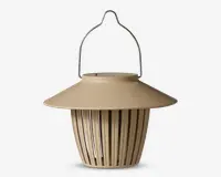 Lysebrun hængende lanterne med bred, skrånende top og lodrette lameller på siderne. Lanternen har et metalhåndtag for nem ophængning og et moderne, minimalistisk design. De åbne lameller på siderne lader lyset skinne igennem og skaber en dekorativ effekt.