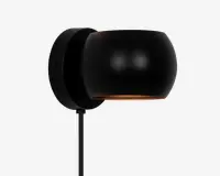 Væghængt armatur i mat sort med en rund, skålformet skærm. Skærmen leder lyset nedad og giver en fokuseret belysning. Armaturet har et minimalistisk design med en glat overflade og skjult monteringsplade, hvilket giver et moderne og stilrent udtryk.