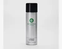 En høj, cylindrisk sølvfarvet spraydåse med sort låg. Dåsen har et grønt logo og mærket 'Guardian Furniture Care' trykt på forsiden. Nederst på etiketten står der 'Laminate Cleaner' med fed sort skrift, og der er yderligere tekst med mindre skrift nedenunder. Designet er stilrent og moderne med børstet metalfinish.