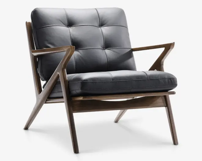 Stol med et design inspireret af mid-century modern stilen, solid træramme og skråtstillede ben. Sæde og ryglæn er polstret med mørkt, knappet læder og synlige stikninger, hvilket giver et blødt og komfortabelt udtryk. Armlænene er slanke og geometrisk formede, hvilket understreger det stilfulde og moderne look.