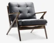 Stol med et design inspireret af mid-century modern stilen, solid træramme og skråtstillede ben. Sæde og ryglæn er polstret med mørkt, knappet læder og synlige stikninger, hvilket giver et blødt og komfortabelt udtryk. Armlænene er slanke og geometrisk formede, hvilket understreger det stilfulde og moderne look.