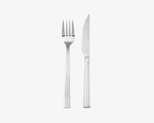 Et sæt bestik i rustfrit stål bestående af en gaffel og en kniv. Begge dele har en blank, reflekterende overflade og håndtag med et lodret, rillet mønster, der giver ekstra greb og elegance. Knivens blad er let takket og egnet til at skære, mens gaflen har fire jævnt fordelte tænder.