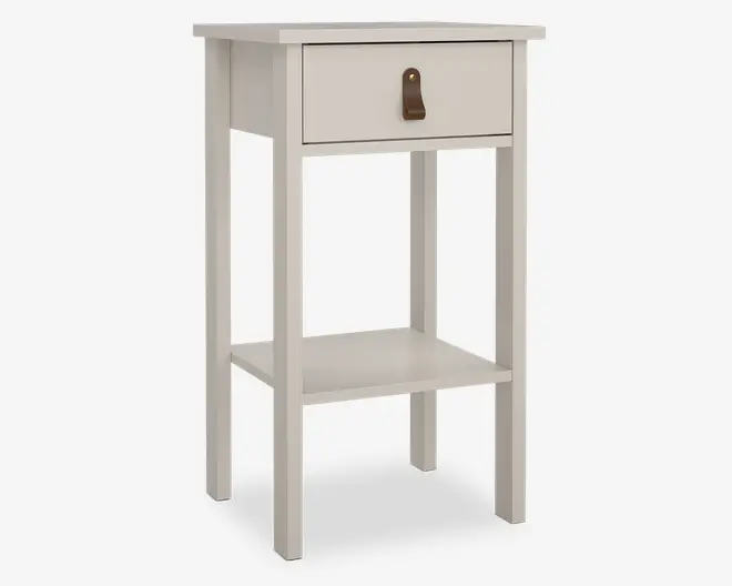 Et lille, rektangulært sidebord med en glat, hvid finish. Bordet har en enkelt skuffe øverst med en brun læderstrop som greb og en messingknap som detalje. Under skuffen er der en åben hylde til ekstra opbevaring. Bordet står på fire lige ben, hvilket giver det et enkelt og moderne udtryk.