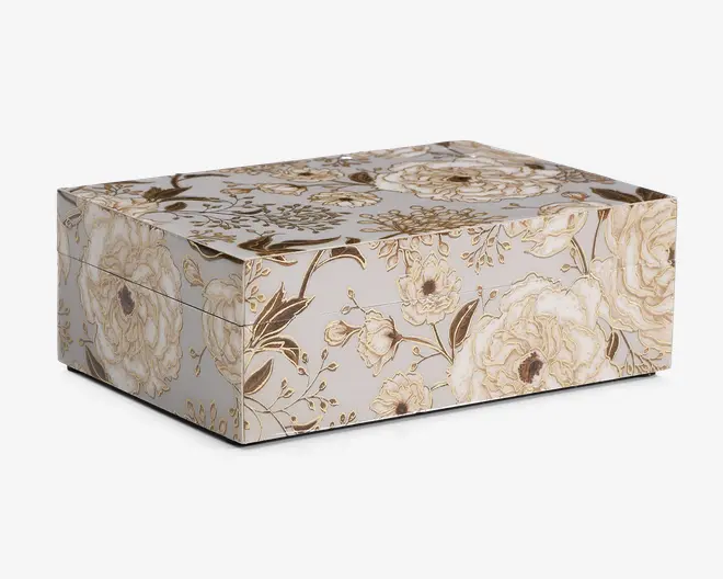 Rektangulær æske med hængslet låg, dekoreret med et elegant blomstermønster i nuancer af beige, creme og guld. Overfladen er prydet med detaljerede illustrationer af roser og blade, hvilket giver et vintage og sofistikeret udseende. Æsken har rene kanter og en glat finish.