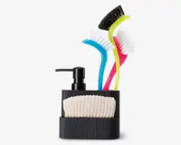 En sort, rillet organizer indeholder en beige strikket rengøringsklud, en sort pumpeflaske og tre opvaskebørster med buede håndtag i blå, gul og pink. Børsterne har hvide børstehår, hvor den gule børste har sorte børstehår på den ene side. Organizeren er kompakt og designet til at holde rengøringsredskaberne pænt organiseret.