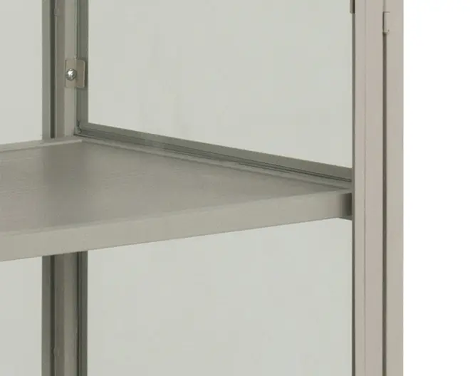 Nærbillede af et hjørne af et skab med en glat, mat metalramme, glas sidepanel og en solid, flad hylde. Hylden ser ud til at være lavet af metal og er understøttet af rammen, hvor synlige skruer holder konstruktionen sammen. Designet er minimalistisk og moderne.