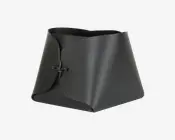 En sort, tekstureret, trapezformet beholder lavet af et enkelt stykke materiale, der er foldet og samlet foran med en simpel knude. Kanterne er glatte, og strukturen er robust med et moderne, minimalistisk design. Åbningen foroven er bred, hvilket gør det nemt at få adgang til indholdet.