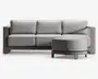 Moderne hjørnesektion med højrevendt chaiselong. Sofaen har tykke, lysegrå hynder med let tekstur, understøttet af en solid, kantet ramme i en matchende neutral farve. Designet har brede armlæn og lav ryg, hvilket giver et moderne og komfortabelt udtryk.